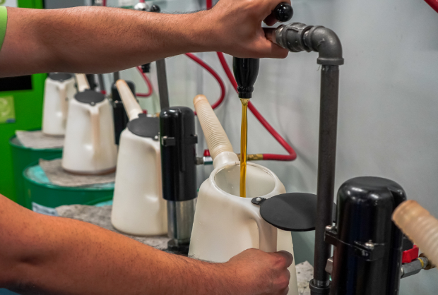 Person pouring lube oil from a tap into a container
